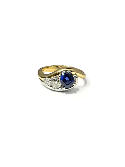 custom Gold ring with a blue sapphire and smaller diamonds on a white background