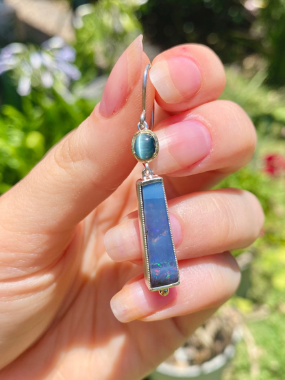 hand holding an earring with green tourmaline and blue boulder opal set in yellow gold and silver