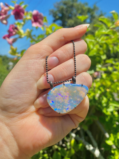 purple lightning ridge boulder opal pendant with blackened silver Glasshouse Mountains held in hand