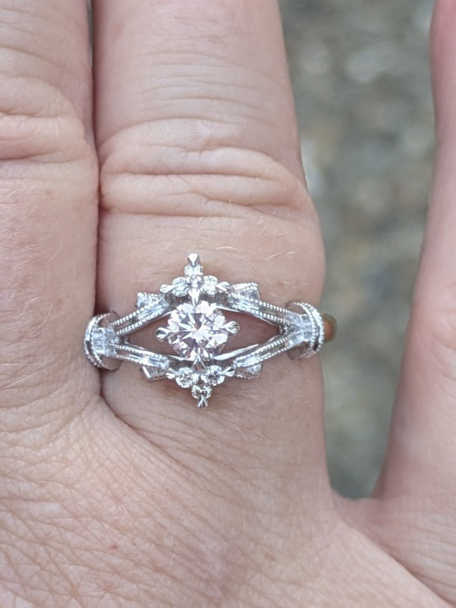 Silver and gold vintage style ring with a diamond on a finger against a blurred background