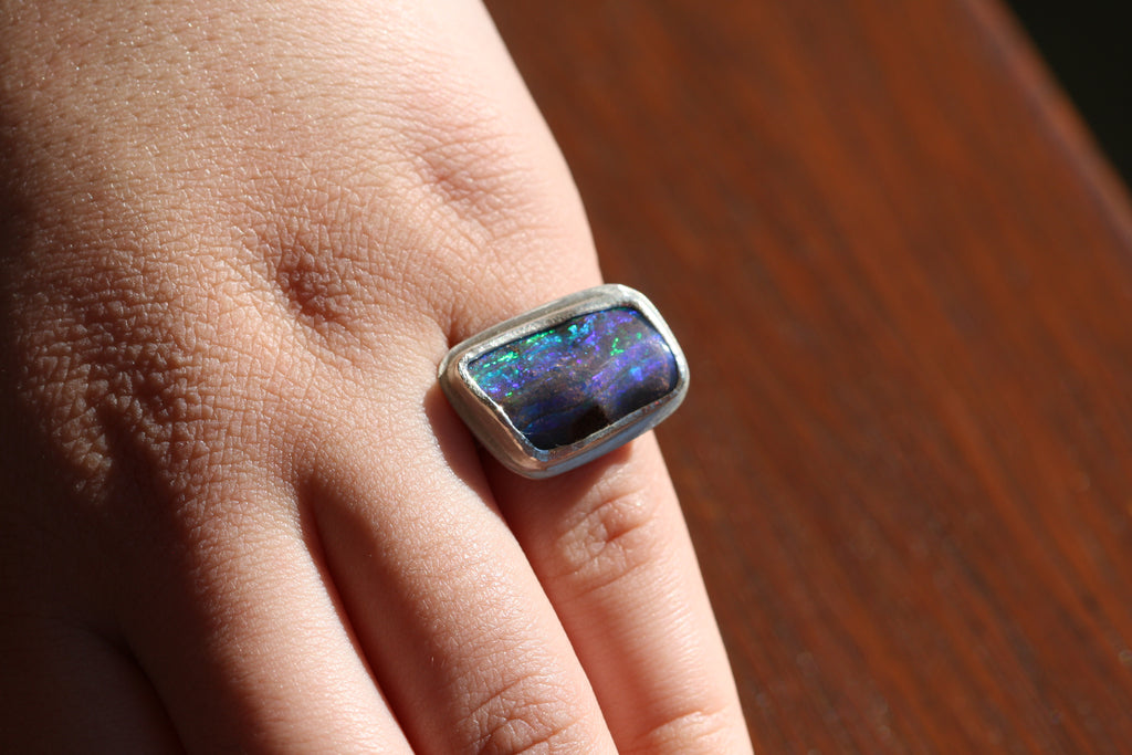 Photo on hand. Australian made and handcrafted in our Brisbane, ethical jewellery made from local products. Silver ring with a textured setting and a blue and green qld boulder opal.