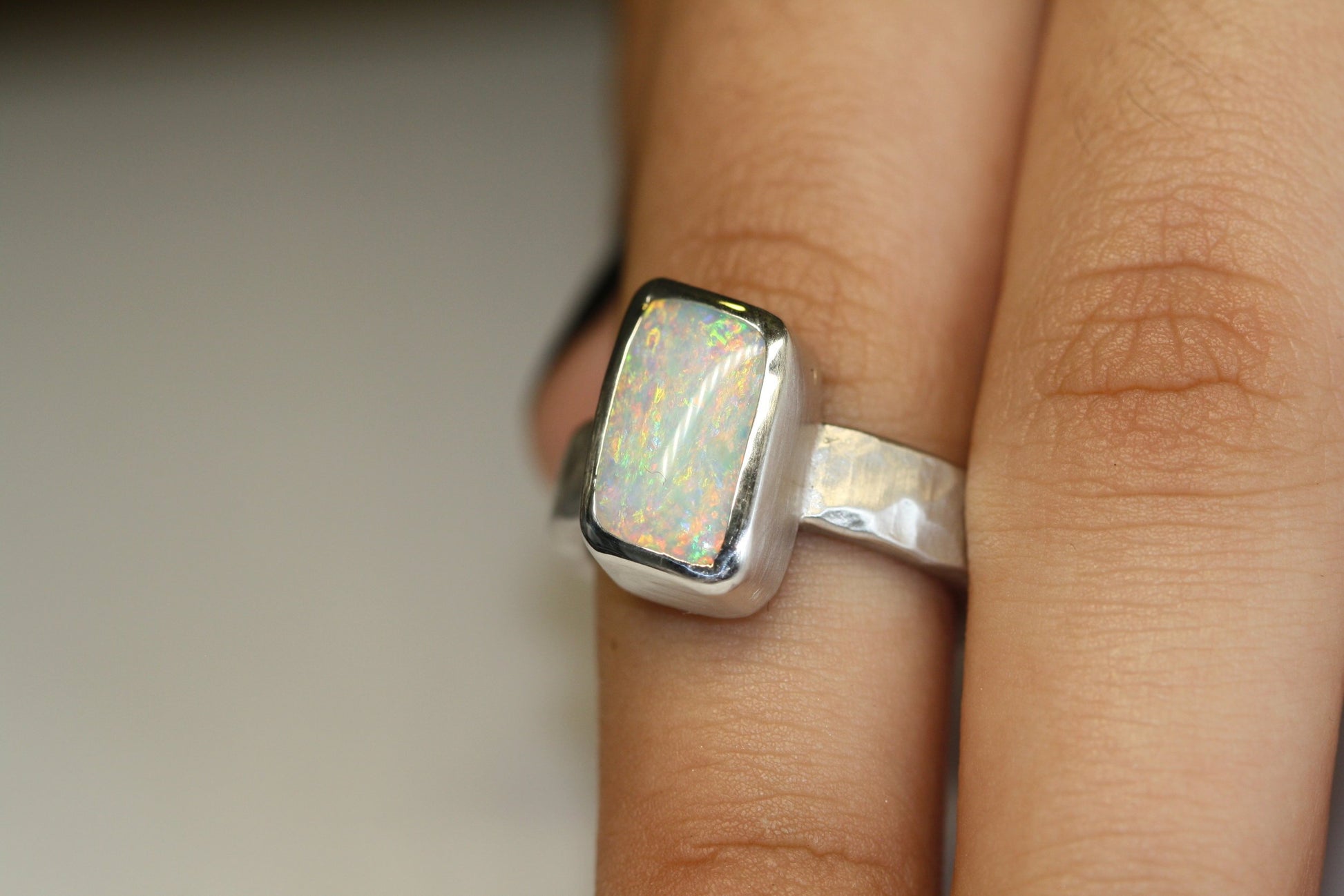 Photo on hand. Queensland Boulder Opal Sterling Silver Ring. Light opal hand crafted in Brisbane Studio using ethically sourced materials. Wide textured band with a hammered finish. Stone is white pink and green. 