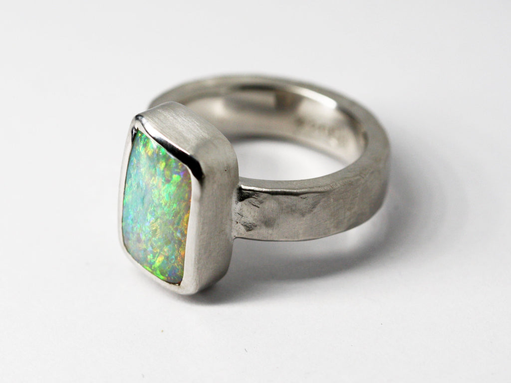 Queensland Boulder Opal Sterling Silver Ring. Light opal hand crafted in Brisbane Studio using ethically sourced materials. Wide textured band with a hammered finish. Stone is white pink and green. 