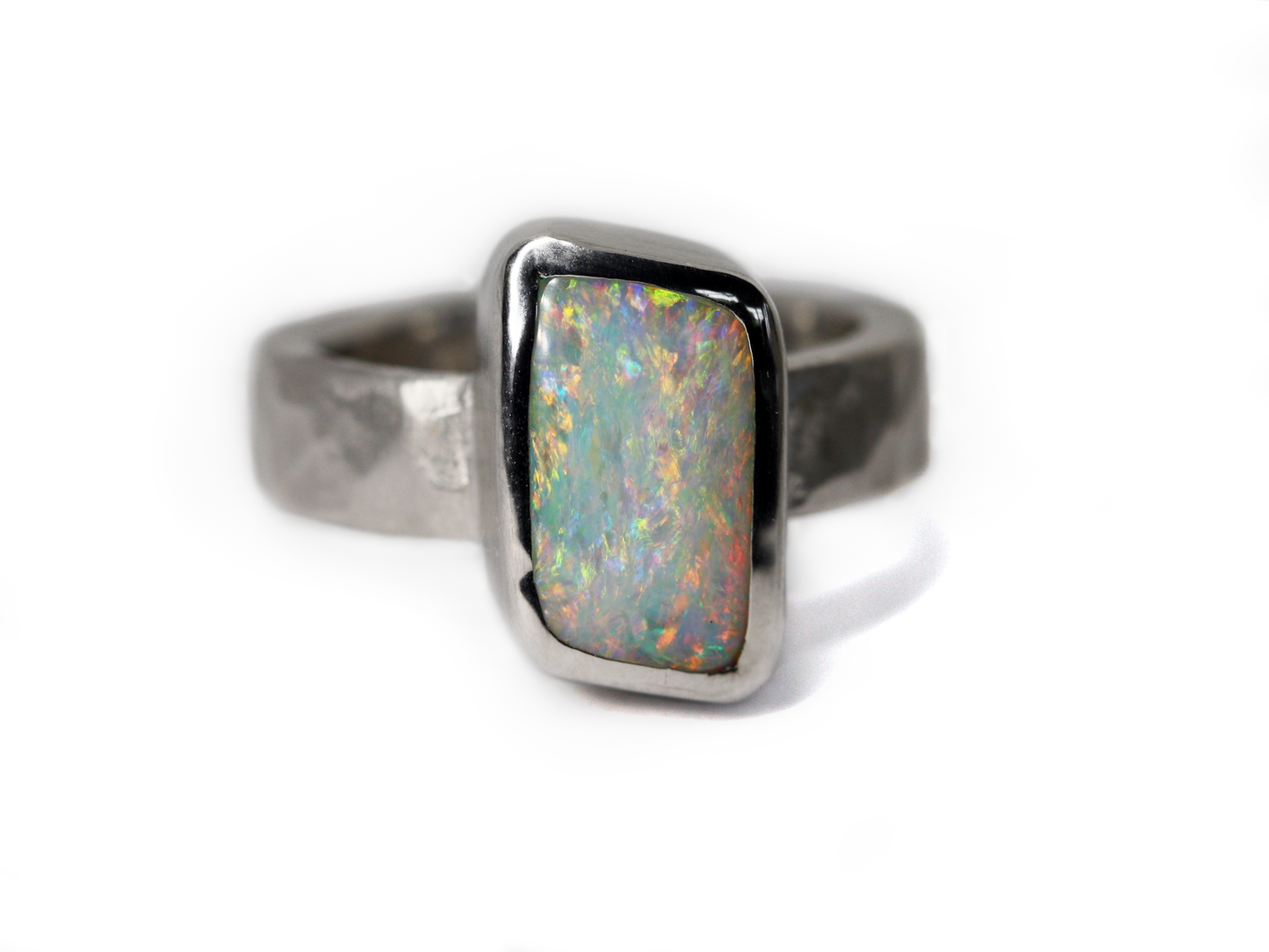 Queensland Boulder Opal Sterling Silver Ring. Light opal hand crafted in Brisbane Studio using ethically sourced materials. Wide textured band with a hammered finish. Stone is white pink and green. 