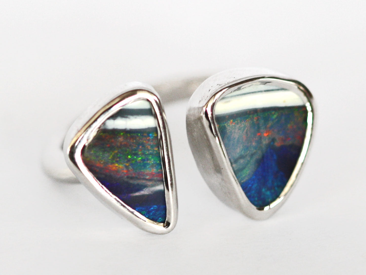 Silver Queensland boulder opal ring. Double Opal set in smooth polished silver. High quality, Australian made by Custom Jewellery Co in our Brisbane studio. Hand crafted using local and ethical materials. Opal is blue with strip of white, has reds, greens and purples shining in the stones. Each stone is a triangle shape