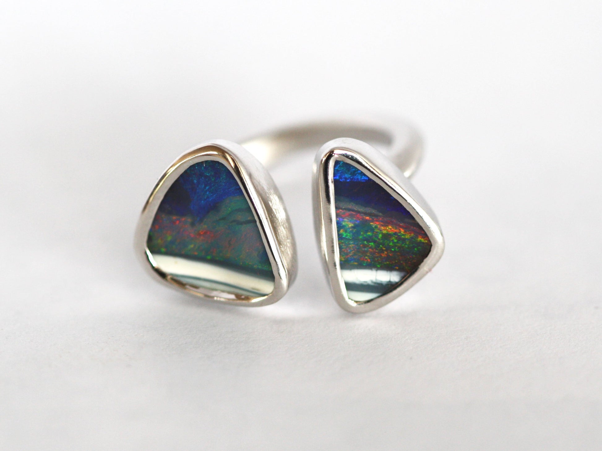 Silver Queensland boulder opal ring. Double Opal set in smooth polished silver. High quality, Australian made by Custom Jewellery Co in our Brisbane studio. Hand crafted using local and ethical materials. Opal is blue with strip of white, has reds, greens and purples shining in the stones. Each stone is a triangle shape