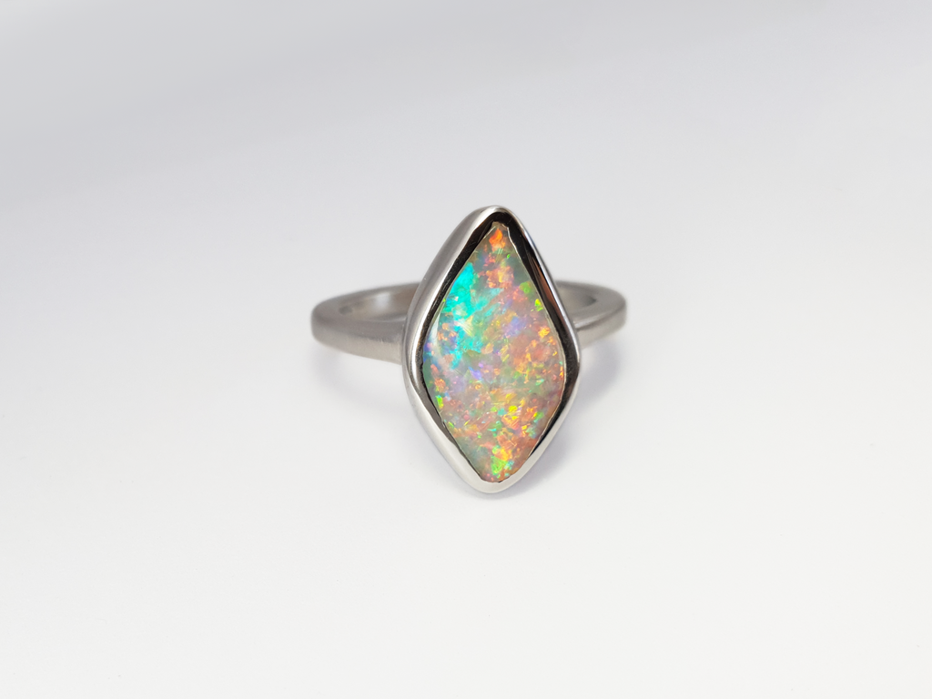 Luminescent Solid Crystal Pipe Queensland Opal. This ultra glittering opal is set in a smooth silver ring with a satin finish to offset the bright sparkly opal. Shining bright green, aqua, pink and orange sherbet flashes. The unique diamond shape sits low and smooth on your finger. Our products are all made with ethically sourced materials and handcrafted in our Brisbane based studio. Australian designed and Australian made for a high quality finish, fine fashion. 